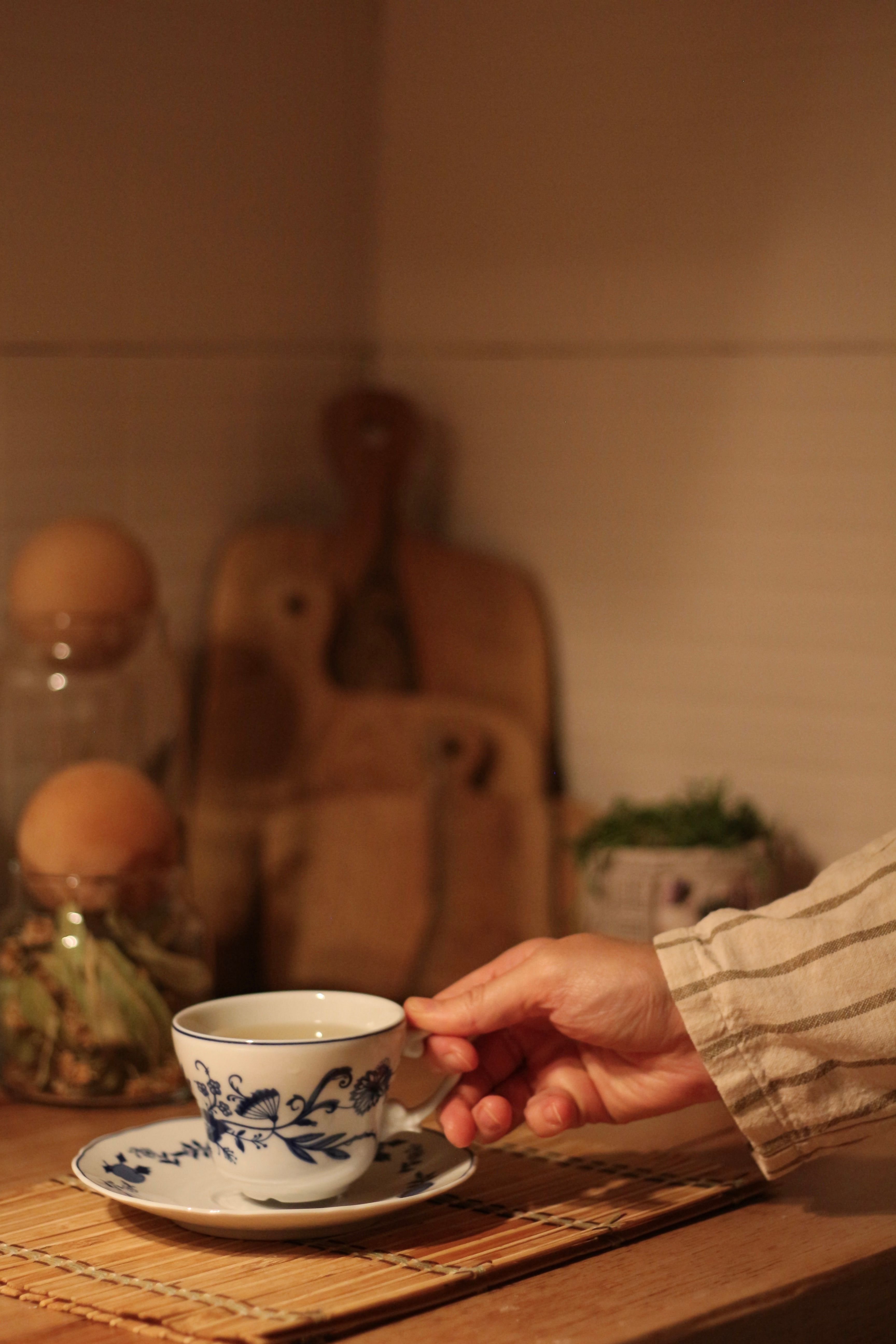 Original photo of a hand holding a patterned cup on its saucer